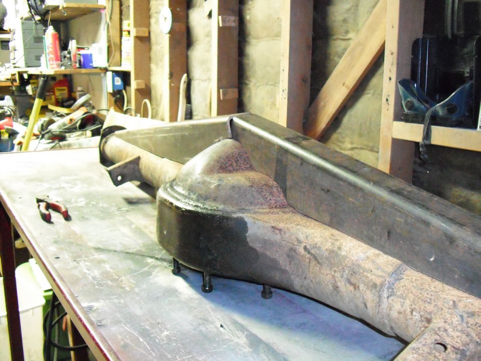 Rusty bare solid axle housing on a shop workbench with diff studs exposed