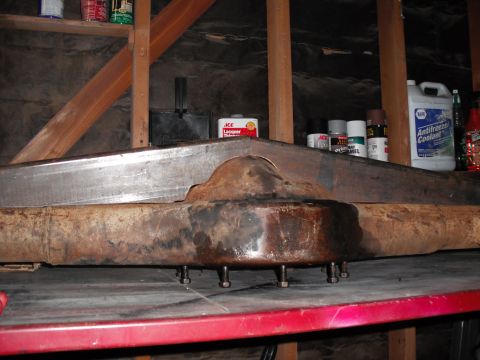 1991 Ford Bronco - Close-up of a rusty axle housing, likely a component for a vehicle, resting on a workbench.
