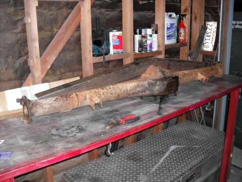 1991 Ford Bronco - Axle housing and differential assembly resting on a workbench in a garage setting.