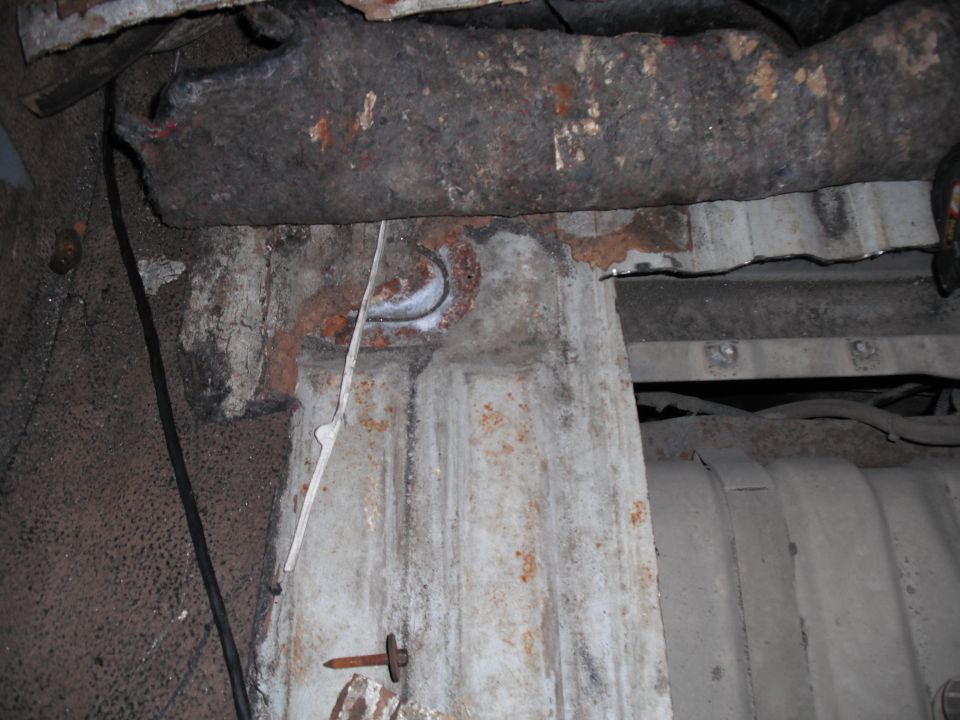 Rusty underbody with visible fuel tank and structural components