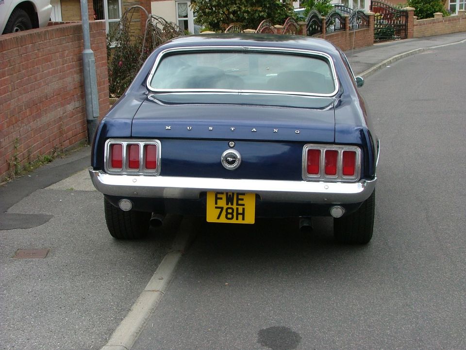 Dark blue 1969 Ford Mustang rear view, chrome bumper, yellow license plate FW E 78H