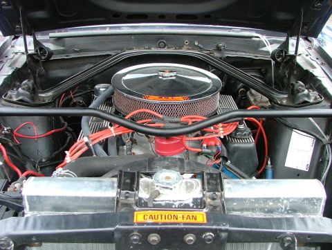 1970 Ford Mustang - Engine bay view of a 1970 Ford Mustang, a chrome air cleaner and prominent red spark plug wires.