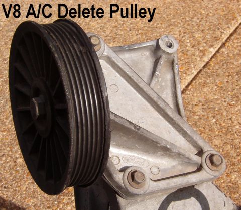 V8 A/C delete idler pulley and bracket on pavement labeled V8 A/C Delete Pulley
