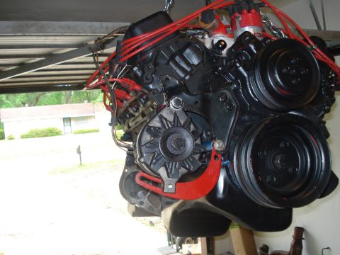 1978 Ford Bronco - Engine assembly hanging from a chain, showing various components and wiring.