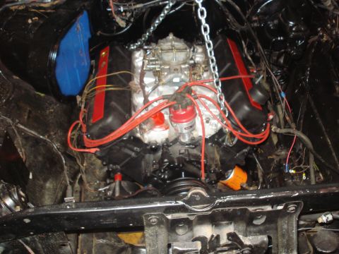 1978 Ford Bronco - Engine assembly with a carburetor and distributor, suspended by a chain for installation or removal.