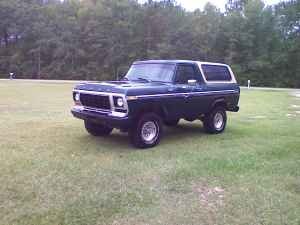1978 Ford Bronco - A dark blue 1978 Ford Bronco is shown from a three-quarter front view, parked outdoors on a grassy area.
