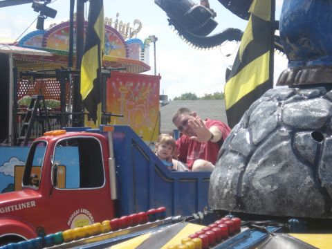 2000 Ford Crown Victoria - A man and two children ride a colorful truck-themed amusement park attraction.