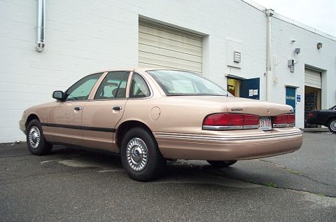 2001 Ford Crown Victoria - Rear view of a tan 2001 Ford Crown Victoria parked next to a commercial building.
