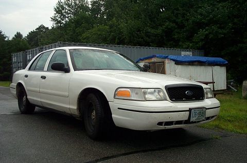 2001 Ford Crown Victoria - A white 2001 Ford Crown Victoria is parked outside on a cloudy day.
