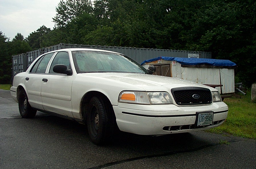 White 2001 Ford Crown Victoria parked on wet asphalt, front 3/4 view
