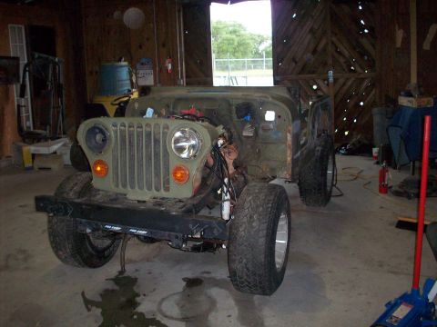 1978 Jeep CJ5 - A green 1978 Jeep CJ5 is shown in a garage, appearing to be undergoing restoration or repair.