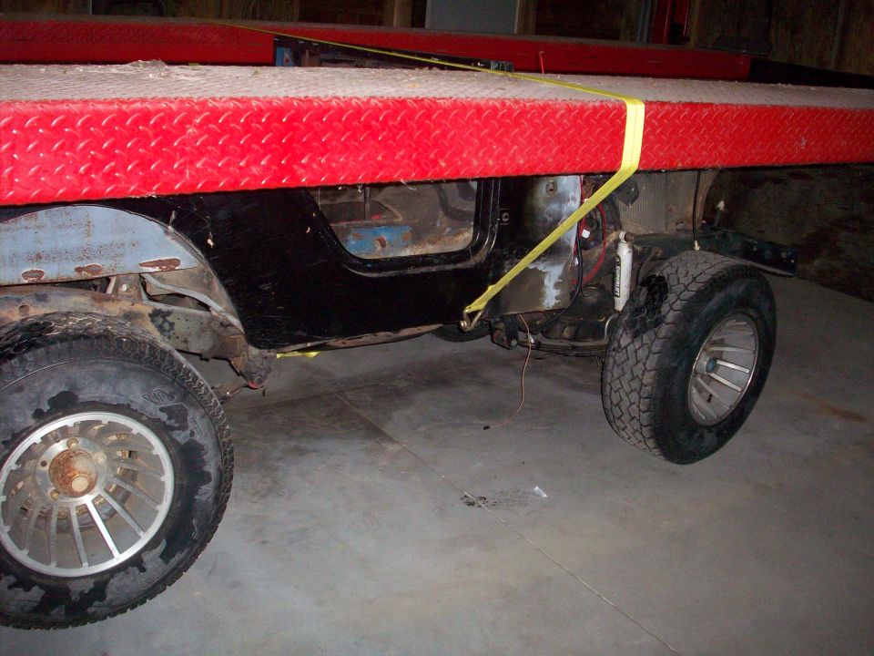 1978 Jeep CJ5 body with black doors and silver wheels, strapped to a red platform