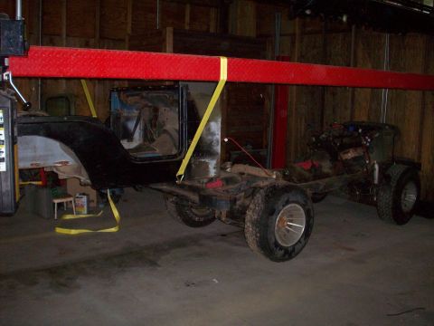 1978 Jeep CJ5 - A Jeep CJ-series chassis is being worked on, suspended by straps in a garage.