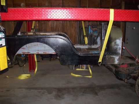 1978 Jeep CJ5 - The body of a 1978 Jeep CJ5 is suspended by straps on a lift, revealing its side profile and interior structure.