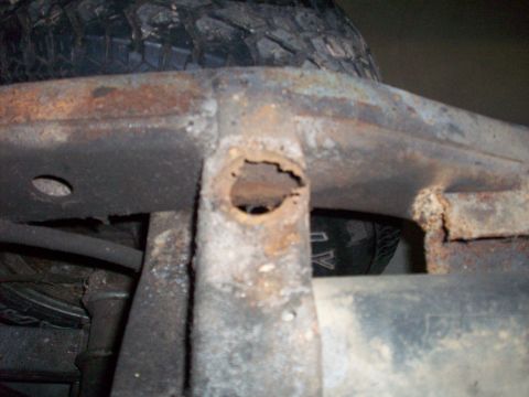 1978 Jeep CJ5 - Close-up view of a heavily rusted vehicle frame section, with a tire visible in the background.