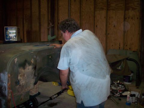1978 Jeep CJ5 - Person working on the body of a vehicle in a garage setting.