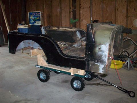 1978 Jeep CJ5 - The body of a Jeep CJ is mounted on a dolly, appearing to be in a state of repair or restoration.
