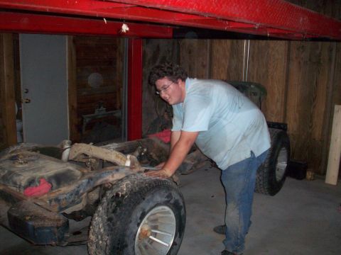 1978 Jeep CJ5 - A man works on the frame of a Jeep CJ in a garage.