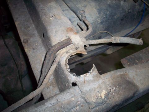 1978 Jeep CJ5 - The rusted frame of a vehicle shows significant corrosion and damage, with fuel lines running across it.