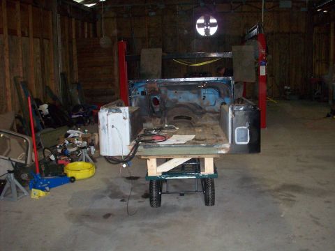 1978 Jeep CJ5 - The body of a Jeep CJ is mounted on a cart, showing its disassembled state within a workshop.