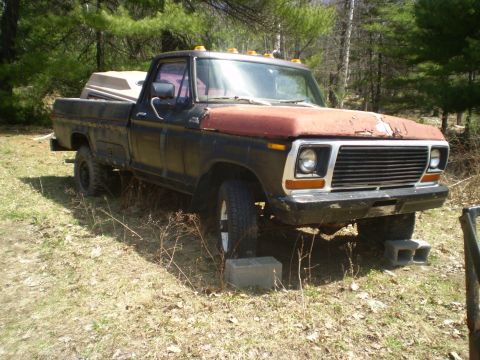 1979 Ford Bronco - This pickup truck, likely from the late 1970s, is parked outdoors with its hood showing significant rust.