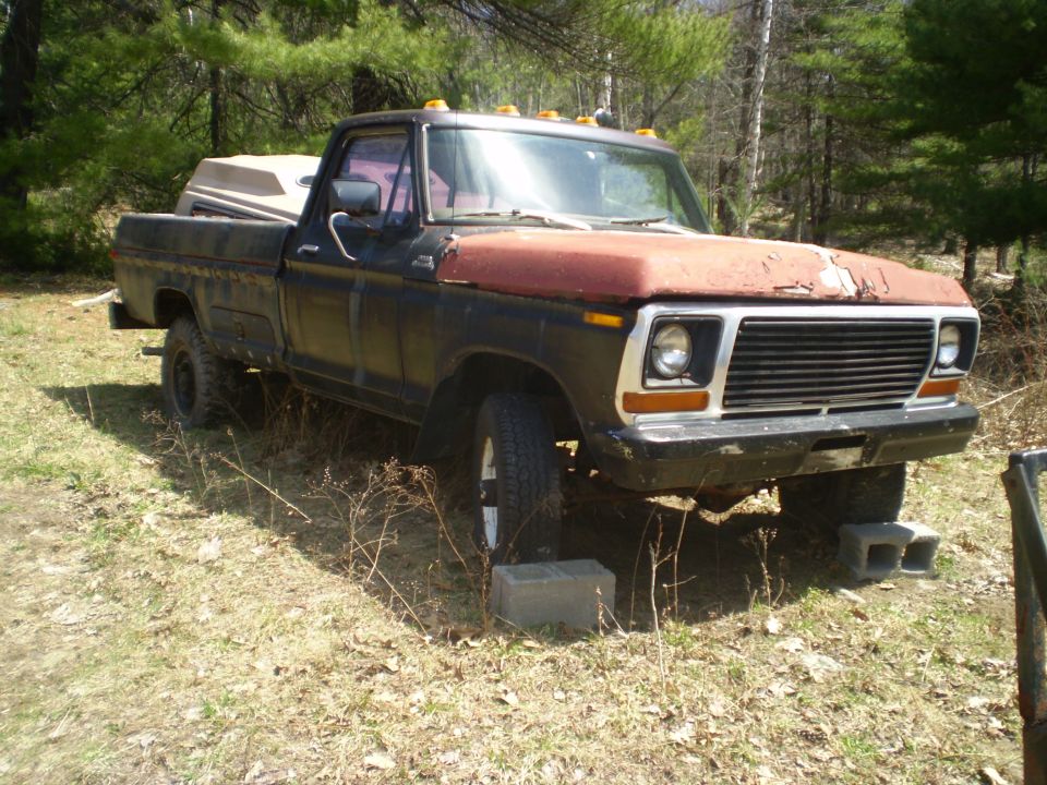 Black and red pickup truck, 3/4 front view. Hood is rusty red