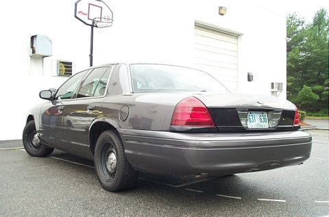 2001 Ford Crown Victoria - A 2001 Ford Crown Victoria sedan is parked outside a building with a basketball hoop visible.