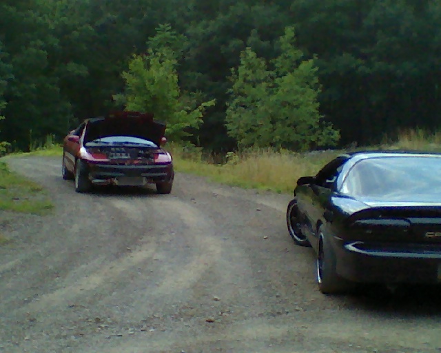 red car with hood up and black car on dirt road