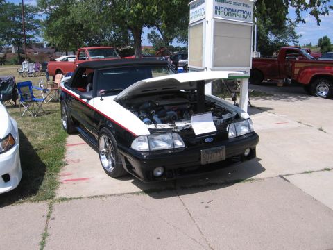 2001 Chevrolet Silverado 1500 - A black and white convertible Mustang is displayed with its hood open, revealing the engine bay. Other vehicles are visible in the backgrou…