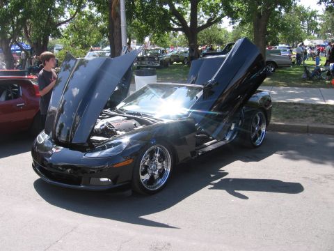 2001 Chevrolet Silverado 1500 - A black sports car with its hood and doors open is displayed outdoors, with other vehicles and people in the background.