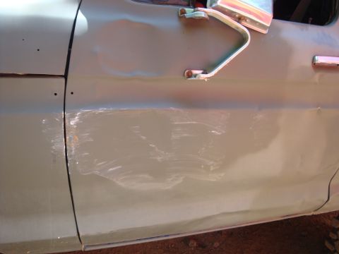 1978 Ford Bronco - A close-up of a damaged vehicle door shows significant dents and scuff marks.