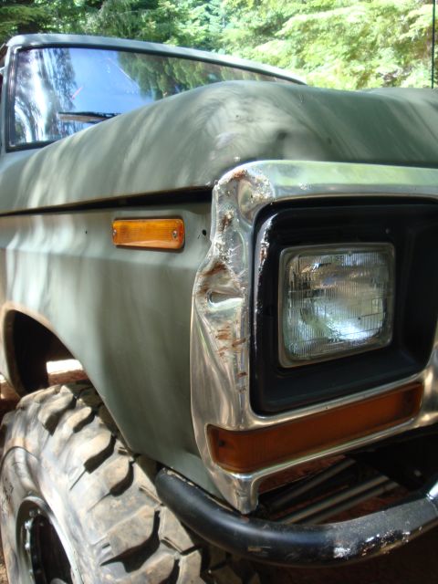 1978 Ford Bronco - Front corner of a 1978 Ford Bronco shows damage to the chrome bumper and fender, with a large off-road tire visible.