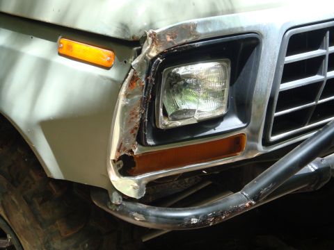 1978 Ford Bronco - The front corner of the vehicle shows significant damage and rust around the headlight assembly and fender.