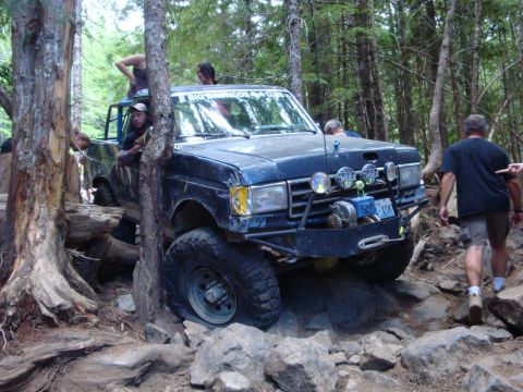 1978 Ford Bronco - Off-road vehicle carefully maneuvers through a challenging rocky obstacle course in a wooded area.