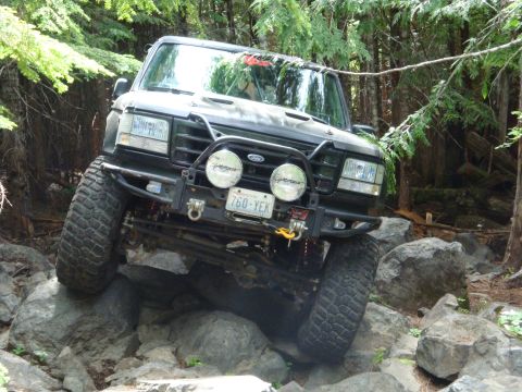 1978 Ford Bronco - This modified Ford Bronco navigates a challenging rocky terrain in a forest setting.