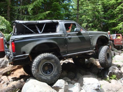 1978 Ford Bronco - This modified SUV navigates a challenging rocky trail with another vehicle visible in the background.