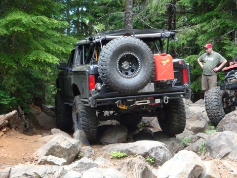 1978 Ford Bronco - A modified 1978 Ford Bronco tackles a challenging rocky trail, equipped with a spare tire and auxiliary fuel can.