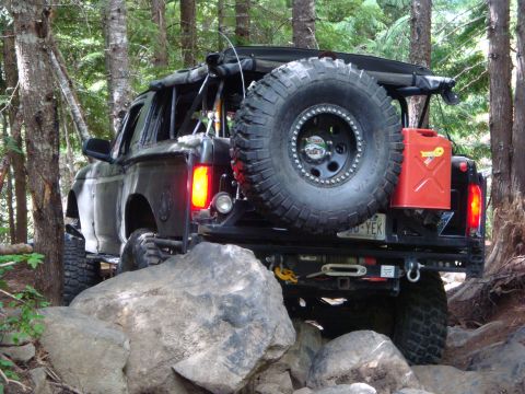 1978 Ford Bronco - This modified SUV navigates a challenging rocky trail, its rear view dominated by a spare tire and fuel can.