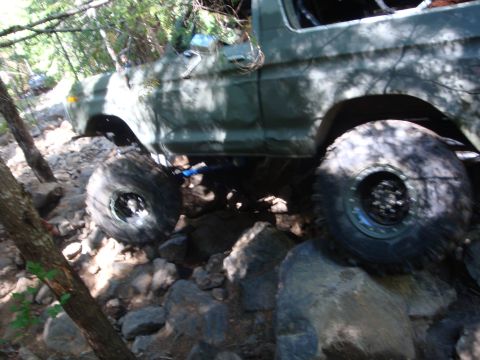 1978 Ford Bronco - This vehicle is shown off-roading on a difficult, rocky terrain with trees surrounding it.