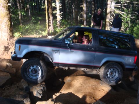 1978 Ford Bronco - Ford Bronco II tackles a challenging off-road trail in a wooded area.