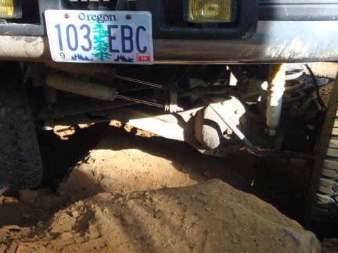 1978 Ford Bronco - The vehicle's front suspension and tires are partially buried in dirt, with an Oregon license plate visible.