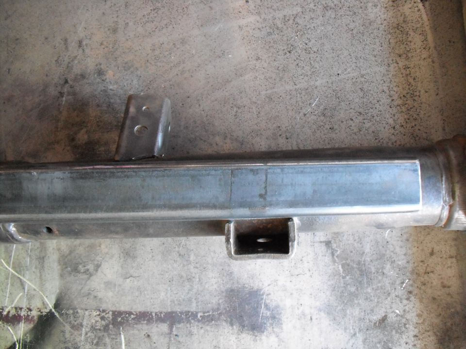 Bare-metal axle tube with welded two-hole bracket and U-shaped perch on concrete