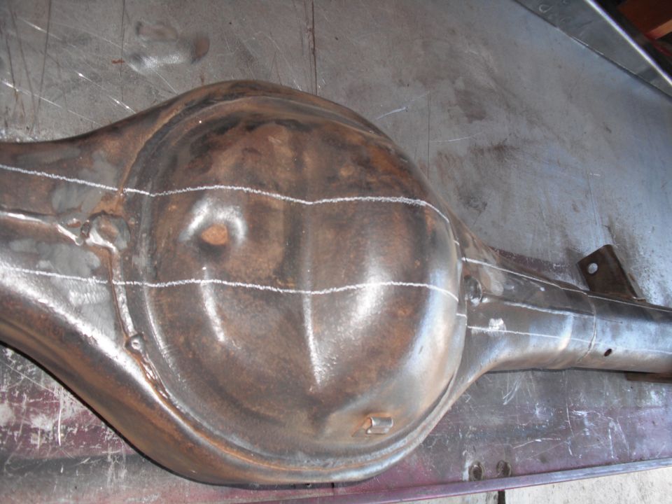 Bare-metal rear axle housing with white chalk layout lines across the diff bowl