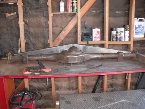 1991 Ford Bronco - Rear axle assembly, possibly for a Ford Bronco, sits on a workbench in a garage.