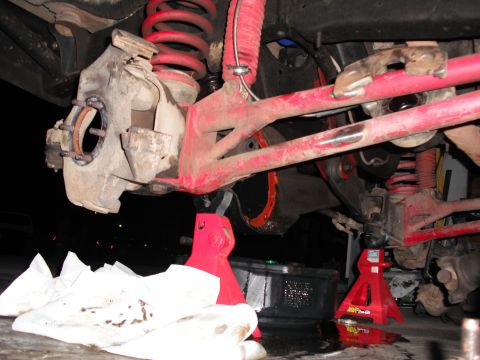 1991 Ford Bronco - Close-up of vehicle suspension parts during maintenance, showing red springs and shocks.