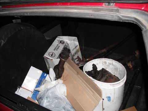 1991 Ford Bronco - Various vehicle parts are stored in the back of a red vehicle.