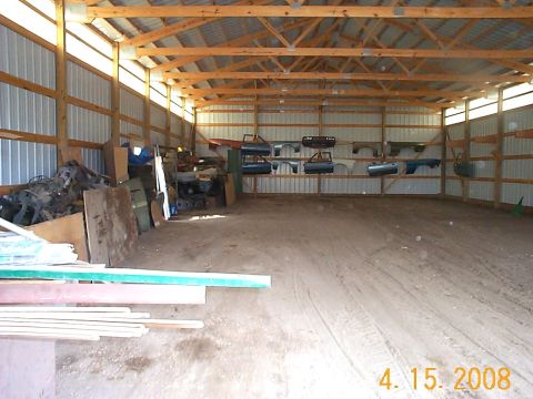 1984 Ford Mustang - Various car doors and fenders are organized and stored on shelves within a large barn structure.