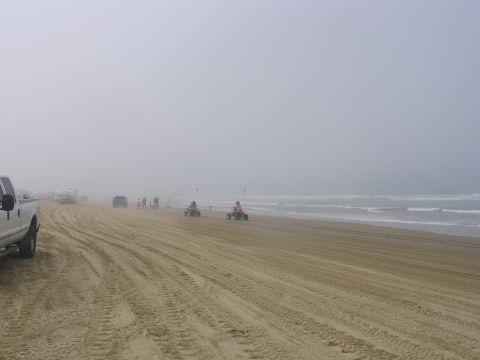 1989 Ford Bronco - A foggy day at the beach with several vehicles and people enjoying the shore.