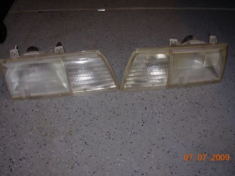 1995 Ford Taurus - A pair of headlights are shown, likely for a car, resting on a garage floor.