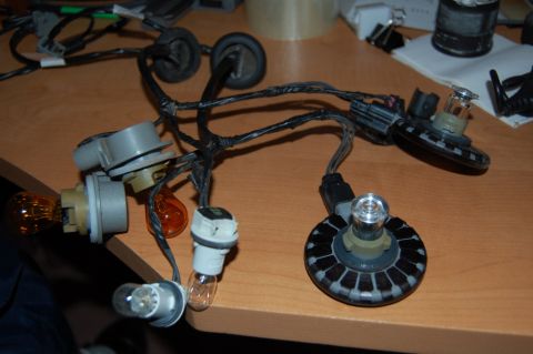 1985 Mercury Grand Marquis - A collection of automotive light bulbs and their wiring harnesses are laid out on a table.